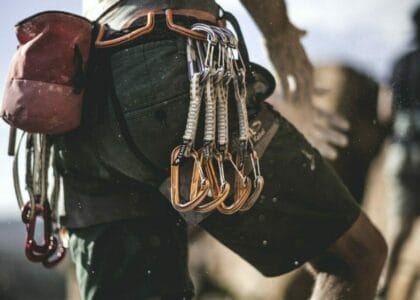 Close up of a mountaineer wearing rope, carabiners, and carabiners on his belt.